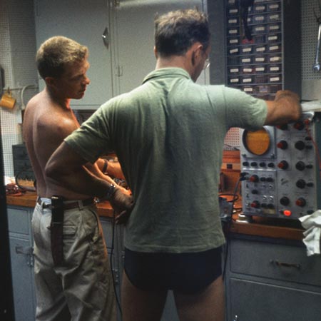 Unidentified lab technicians of the Swan Song Expedition (1961) are shown here setting the electronic TDS meter on board the R/V Argo during the Swansong Expedition (1961). 1961.