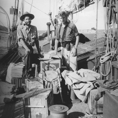[Two men standing surrounded by supplies on deck of R/V E.W. Scripps]